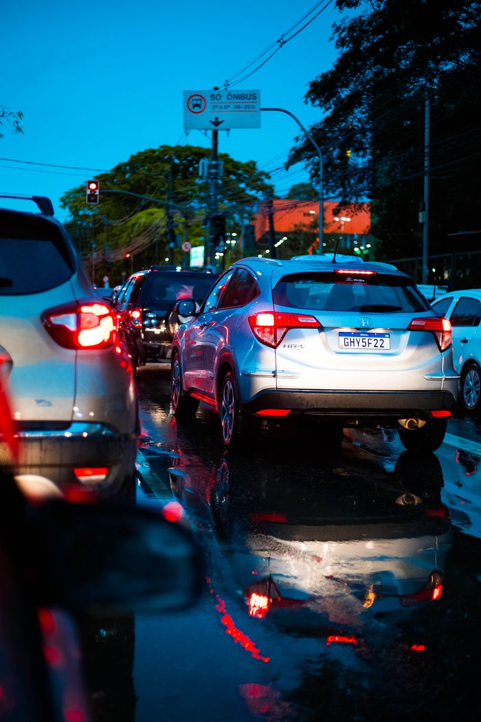 Cars in traffic at sunset reflecting on wet streets, creating a dynamic urban scene.
